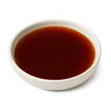 Dark brown regular cola with a few fine bubbles in a low warm off-white ceramic condiment dish
