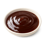Thick glossy dark-brown oyster sauce in a low matte cream ceramic condiment dish on a pure white background.